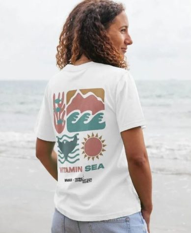 ocean-themed gifts A woman at the beach wearing a white shirt with a print