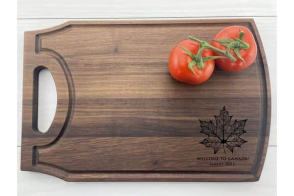 A wooden cutting board with a maple leaf engraved