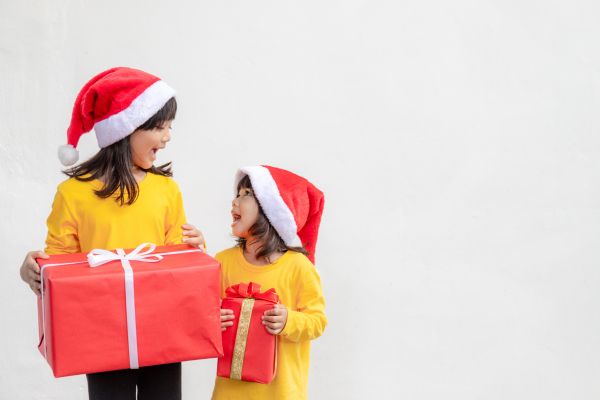 fun facts about presents Two kids with Christmas hats and gifts in their hands