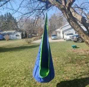 A pod swing for kids hanging from a tree