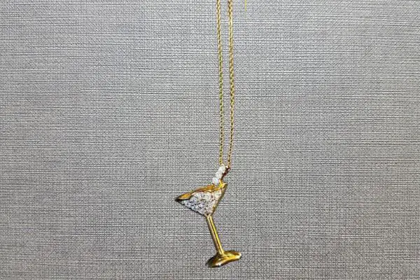 A golden necklace with a pendant of a martini glass
