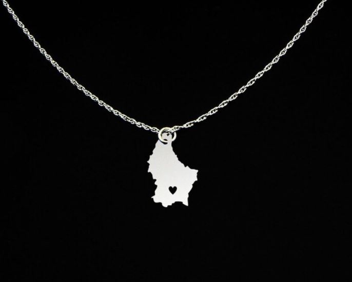 A silver necklace with a pendant in the shape of the map of Luxembourg