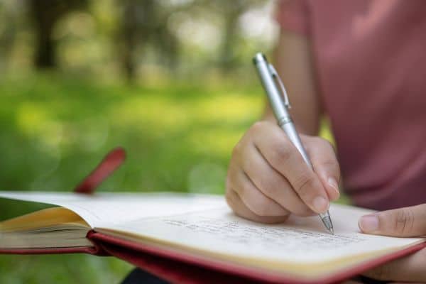 Someone writing on a notebook