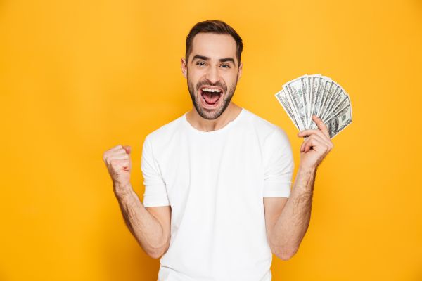 A man smiling and holding cash in his hands