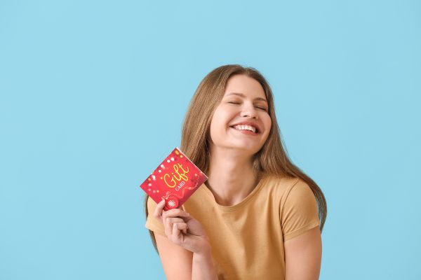 A woman smiling and holding a gift card in her hand